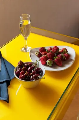 a plate of strawberries and a glass of wine on a yellow table at Allegory Boutique Hotel in Rhodes Town