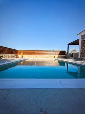 a swimming pool with blue water in a yard at Mandilaria stone house in Afantou