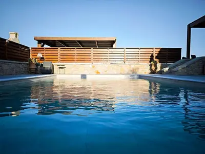 a swimming pool with blue water in front of a building at Mandilaria stone house in Afantou