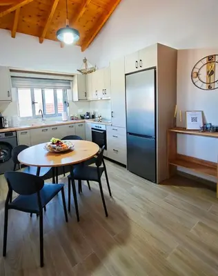 a kitchen with a table and chairs and a refrigerator at Mandilaria stone house in Afantou