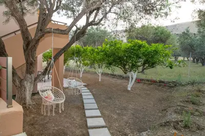 a garden with two chairs and a swing under a tree at Casa Serena in Lardos
