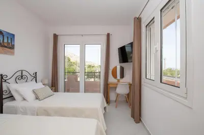 a white bedroom with two beds and a window at Casa Serena in Lardos