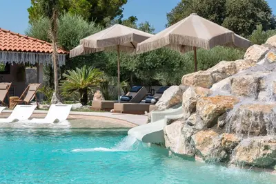 a swimming pool with a waterfall in a resort at Vento Estivo Mansion in Pastida
