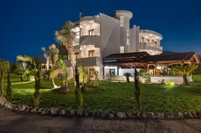a large white building with palm trees in front of it at Vento Estivo Mansion in Pastida
