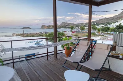 a balcony with white chairs and a view of the ocean at Barbara's Apartments in Vrachonisída touArchangélou