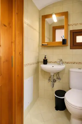 a bathroom with a sink and a toilet and a mirror at Wuthering Mill in Symi