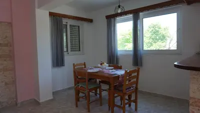 a dining room with a table and chairs and two windows at Sugarcubes by Evagstays in Faliraki