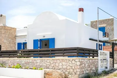 a white house with blue doors and a stone wall at Villa Milla in Gennadi