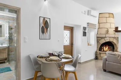 a living room with a table and chairs and a fireplace at VaSteka House 2 in Haraki