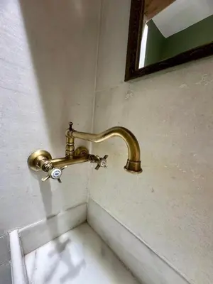 a brass faucet on a wall with a mirror at St John house Castle City in Rhodes Town