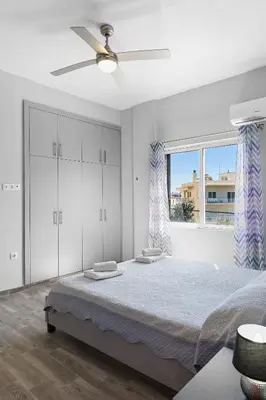 a white bedroom with a bed and a window at City Central Appartment in Rhodes Town