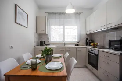 a kitchen with a wooden table and white cabinets at Casa Platoni in Apolakkiá