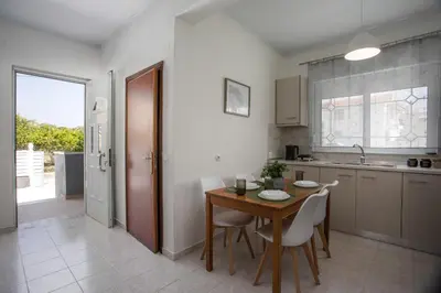 a kitchen with a wooden table and white chairs at Casa Platoni in Apolakkiá