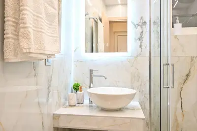 a white bathroom with a sink and a shower at Harmony Studio Apartment in Ialyssos