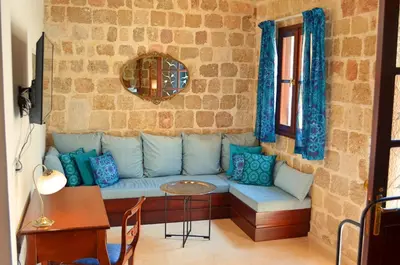 a living room with a blue couch against a stone wall at Hotel Ellique in Rhodes Town