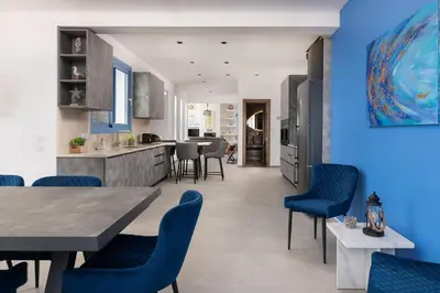 a kitchen and dining room with blue walls and blue chairs at Aitheria Lindos Villa in Líndos