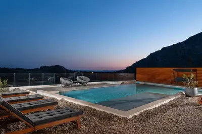 a swimming pool with two lounge chairs next to it at Aitheria Lindos Villa in Líndos
