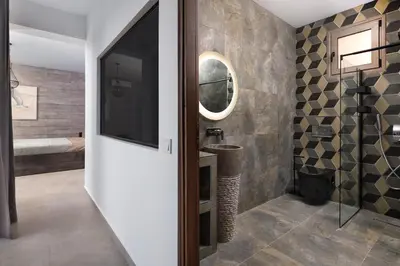 a bathroom with a tv and a sink and a mirror at Aitheria Lindos Villa in Líndos