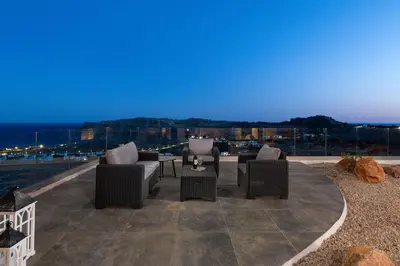 a patio with chairs and tables and a view of the city at Aitheria Lindos Villa in Líndos
