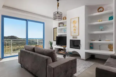 a living room with a couch and a large window at Aitheria Lindos Villa in Líndos