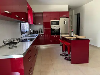 a large kitchen with red cabinets and red bar stools at Angela House in Symi