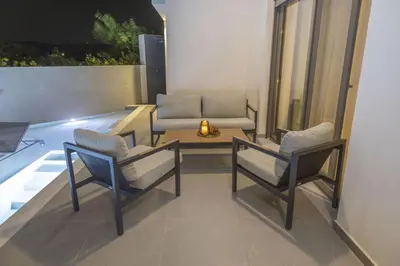 a patio with two chairs and a table and a couch at Villa Viventia with Heated Pool in Afantou