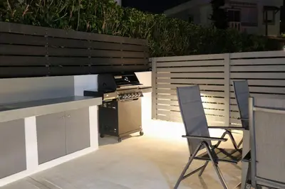 a backyard with a stove and chairs and a fence at Villa Viventia with Heated Pool in Afantou
