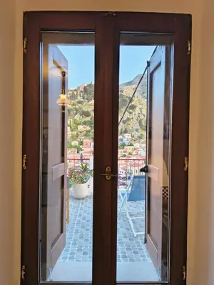 an open door with a view of a city at Lirenou Scala Vista in Symi