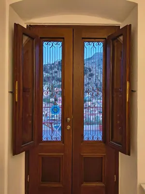 a wooden door with two windows in a room at Lirenou Scala Vista in Symi