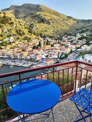 a blue table and chairs on a balcony with a view at Lirenou Scala Vista in Symi