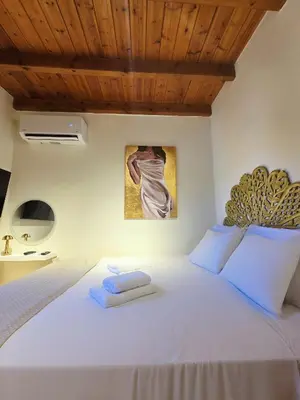 a bedroom with a white bed with a wooden ceiling at Barbarian in Rhodes Town