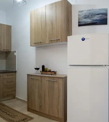 a kitchen with a white refrigerator and wooden cabinets at Filerimos Nest in Pastida