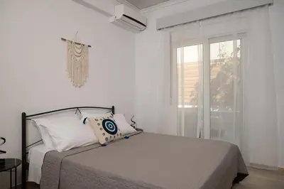 a white bedroom with a bed and a window at Filerimos Nest in Pastida
