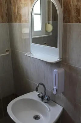 a white sink in a bathroom with a mirror at Melpos Room in Kremasti