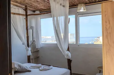 a bedroom with a bed with a view of the ocean at Christos studios and family apartments in Vrachonisída touArchangélou