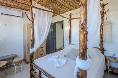 a bedroom with a four poster bed with white sheets at Christos studios and family apartments in Vrachonisída touArchangélou