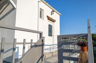 a white house with a blue fence next to it at Christos studios and family apartments in Vrachonisída touArchangélou