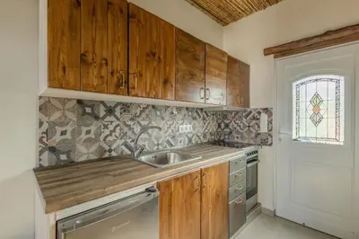 a kitchen with wooden cabinets and a sink at Christos studios and family apartments in Vrachonisída touArchangélou