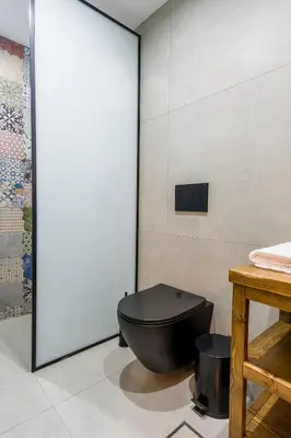 a bathroom with a black toilet sitting next to a wall at To Kamariko in Soroni