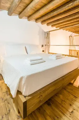 a large white bed in a room with wooden floors at To Kamariko in Soroni