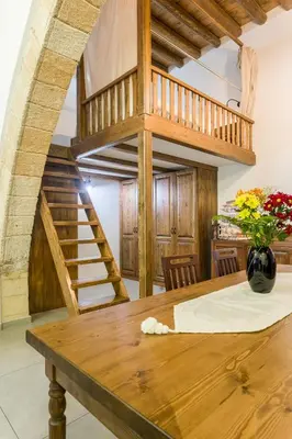 a dining room with a wooden table and a spiral staircase at To Kamariko in Soroni