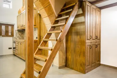 a wooden staircase in a kitchen with wooden cabinets at To Kamariko in Soroni