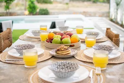a table with plates of food and glasses of orange juice at Sia Villa in Lardos