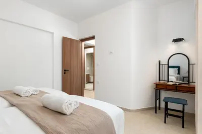 a white bedroom with a bed and a desk at Casa Stefania in Faliraki