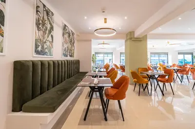 a restaurant with tables and chairs and a green bench at Philia Center Suites in Rhodes Town