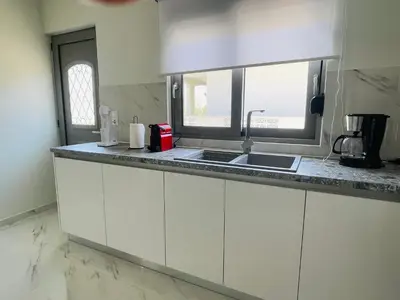 a kitchen with white cabinets and a sink and a window at Anastasia House in Afantou