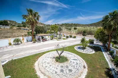a garden with a tree in the middle of a road at Mosaic Garden Anastasias Rooms in Faliraki