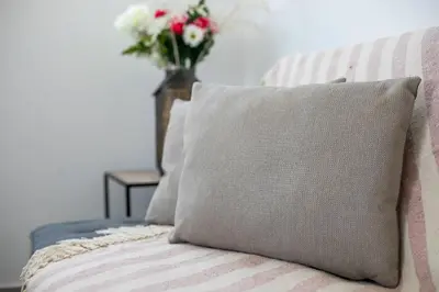 a pillow sitting on a bed with a vase of flowers at Bless View Studios in Lachania