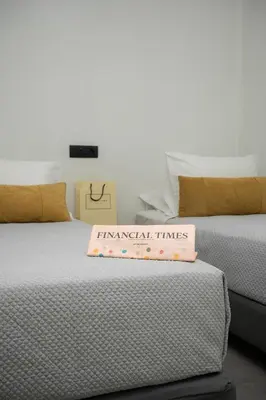 two beds with a sign that reads financial times at Amphitryon City Hotel in Rhodes Town