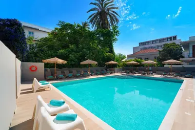 a swimming pool with lounge chairs and umbrellas at Amphitryon City Hotel in Rhodes Town